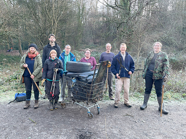 A group of volunteers looking pleased with themselves, in front of a whole shopping trolley of collected rubbish